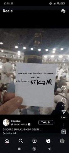 a person is holding a piece of paper that says ' skm ' on it in front of a kaaba