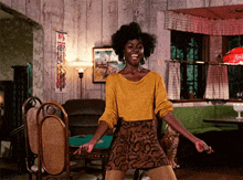 a woman in a yellow shirt and snake print skirt is dancing
