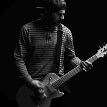 a man in a striped shirt is playing a guitar in the dark