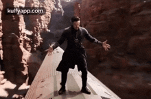 doctor strange is standing on top of a train in a canyon .