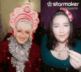 a woman is wearing a santa hat and a woman is wearing a tinsel necklace .