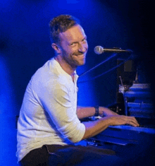 a man is singing into a microphone while playing a piano on a stage .