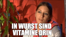 a woman is sitting in front of a plant with the words in wurst sind vitamine drin written on her face .