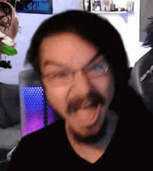 a man with glasses and a beard is making a funny face in front of a computer