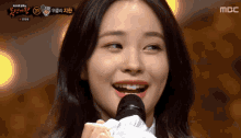 a woman is smiling while holding a microphone in front of a sign that says mbc on it