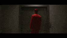 a man in a red suit is standing in a dark elevator