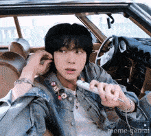 a man in a denim jacket is sitting in a car with headphones on ..