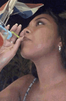 a woman is drinking from a glass with a straw in her mouth