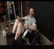 a man in a gray shirt with a skull and crossbones on it is sitting on a machine