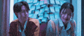 a boy and a girl are sitting next to each other in front of a wall of sticky notes