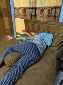 a person in striped pants is laying on a bed with pillows