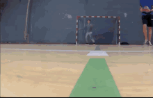 a man is playing a game of handball on a court with a goal in the background