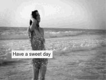 a black and white photo of a woman standing in the ocean with the words have a sweet day written above her