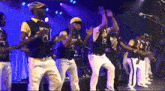 a group of men are dancing on a stage and one of them is wearing a yellow hat that says cabo
