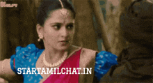a woman in a blue top and a red top is standing in front of a sign that says startamilchat.in