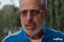 a man with a beard wearing sunglasses and a blue jacket with imgplay written below him