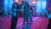 a group of women are dancing together in a room with blue lights