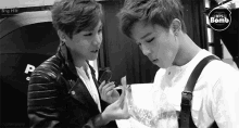 two young men are standing next to each other in front of a sign that says big hit bts bomb