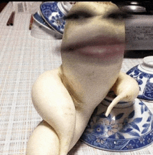 a naked person sitting on a blue and white bowl on a table