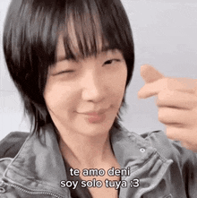 a woman with short hair is making a heart shape with her fingers and says `` te amo deni soy solo tuya '' .