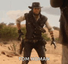 a man in a cowboy hat is standing in the desert holding a gun and a cigarette .