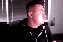a man sitting in front of a window with blinds and a calculator on the wall that says ' calculator ' on it