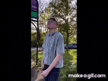 a man wearing glasses and a hat is standing in front of a sign that says ' ashton ' on it .
