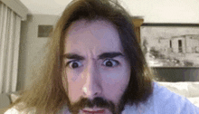 a man with long hair and a beard is making a funny face while looking at the camera .