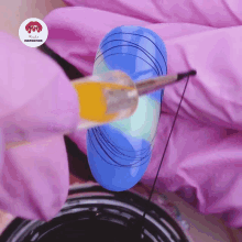 a blue nail with a spider web design is being painted by a person wearing pink gloves