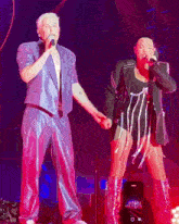 a man and a woman are singing into microphones on a stage at a concert .