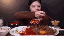 a woman is eating shrimp with chopsticks from a plate .