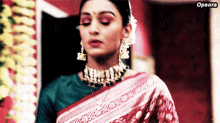 a woman wearing a green shirt and a red and white saree has opsora written on the bottom