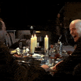 two men sit at a table with lit candles