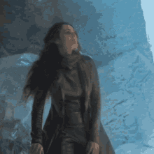 a woman in a black coat stands in a cave