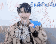 a man is smiling while holding a blue object in front of a firework display .