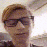 a man wearing glasses is taking a selfie with his eyes closed .