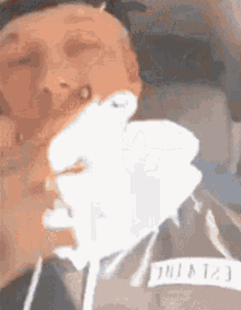 a close up of a person holding a white object in front of their face .