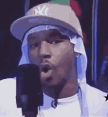 a man wearing a new york yankees hat is singing into a microphone .