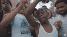 a group of young men are dancing together in a crowd . one of the men is wearing an adidas shirt .