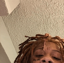 a close up of a person 's face with dreadlocks and a tattoo on their face .