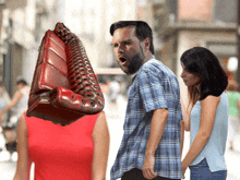 a man with a beard holds a red leather couch over his head while a woman looks on