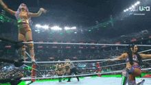 a group of women are wrestling in a ring with a referee in the background .