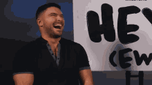 a man is laughing in front of a sign that says " hey crew "