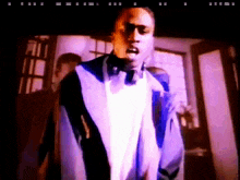 a man in a blue jacket and white shirt is standing in a dark room