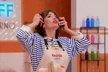 a woman wearing a striped shirt and an apron that says magone