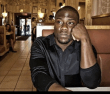 a man in a black shirt is sitting in a booth in a restaurant