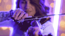 a woman is playing a violin in a purple room