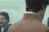 a man in a brown jacket is standing in front of a woman