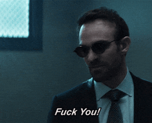 a man wearing sunglasses and a suit says " fuck you "