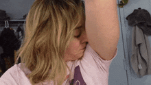 a woman in a pink shirt is smelling her underarm